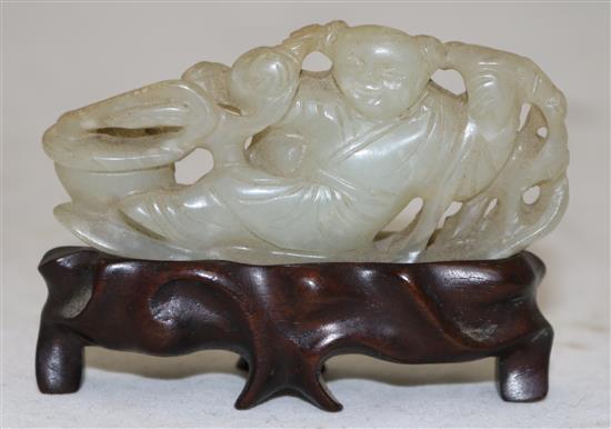 A Chinese pale celadon jade carving of a boy seated on a pine raft, 18th/19th century, 7.1cm, rosewood stand